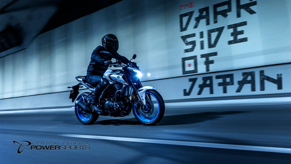 Rider on a 2026 Yamaha MT-03 passing an illuminated city wall