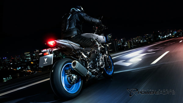 Rear view of a rider on a 2026 Yamaha MT-10 on a city road at night