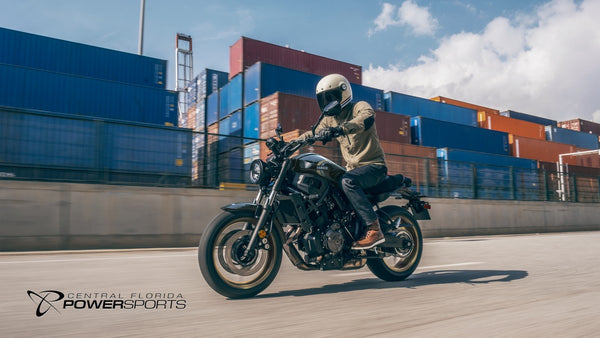 Rider on a 2026 Yamaha XSR700 passing shipping containers